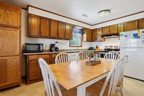 A kitchen with wooden cabinets, a microwave, a coffee maker, and a dining table with chairs.