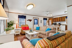 Una sala de estar acogedora con sofás a rayas, un comedor y una cocina.