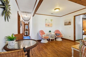 A hallway with a dining area featuring wicker furniture, a small table, and chairs with cushions. - Doris's Day-- 4BR Oceanside home in Duck with Private Hot Tub (Duck)