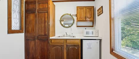 A compact kitchen with wooden cabinets, a microwave, and a sink.