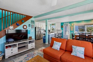 A modern kitchen with white cabinets, a stainless steel refrigerator, and a dining area with a table and chairs. - Surf N Sound -- Pet Friendly 4BR with Ocean and Sound Views in Duck (Duck)
