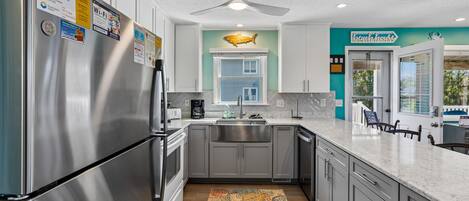 A modern kitchen with stainless steel appliances, a ceiling fan, and a view of the outside.