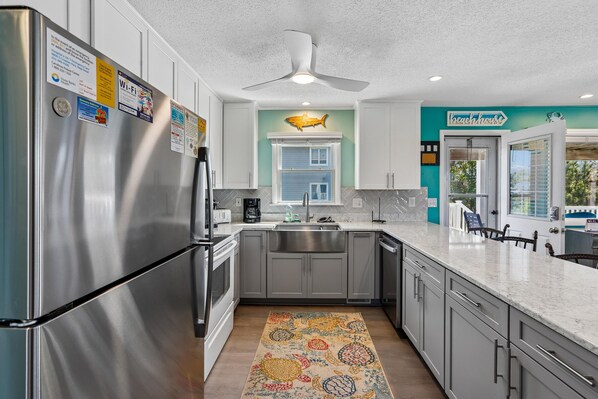 A modern kitchen with stainless steel appliances, a ceiling fan, and a view of the outside.