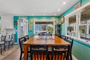 A dining area with a wooden table, black chairs, and a view of the outside. - Surf N Sound -- Pet Friendly 4BR with Ocean and Sound Views in Duck (Duck)