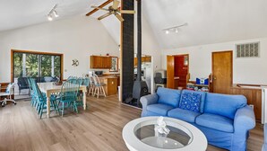 A spacious living area with a dining table, blue sofa, and a ceiling fan. - The Tree House --Flexible Arrival and Stay Dates Year Round (Duck)