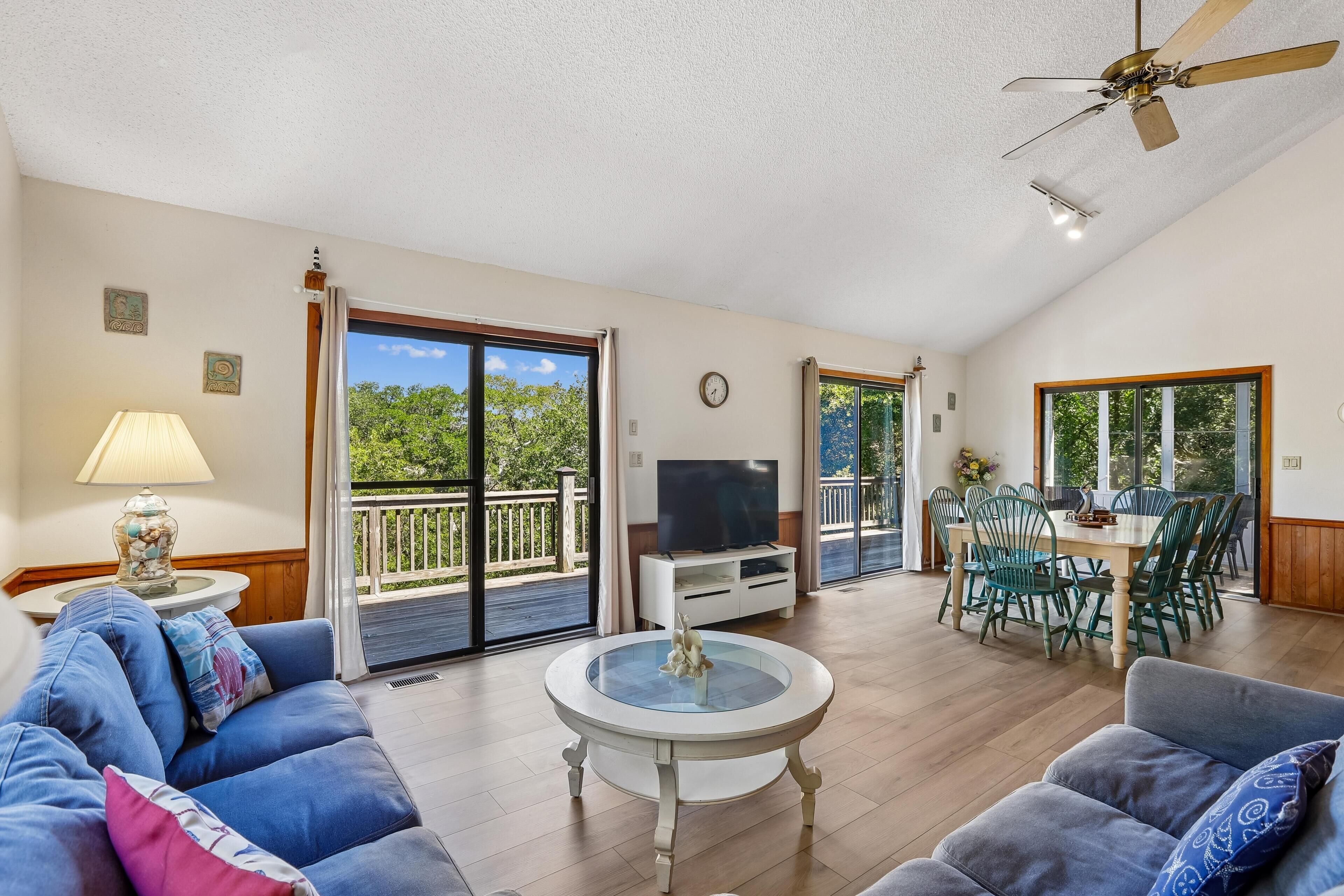 A spacious living room with a sofa, a coffee table, a TV, and a balcony with a dining area.
