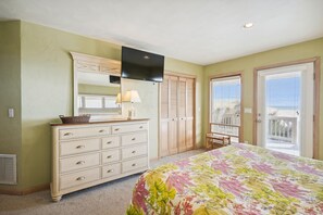 A bedroom with a bed, dresser, mirror, and a window with blinds.