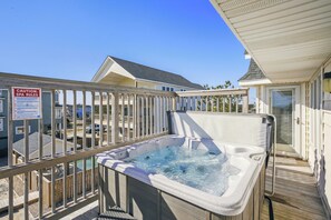 Un bain à remous sur une terrasse en bois, avec vue sur un quartier résidentiel et un panneau indiquant les règles du spa.