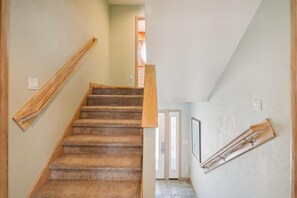 A staircase with carpeted steps and wooden handrails, leading to a door with a window.
