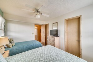 A room with two beds, a ceiling fan, a television on a dresser, and a door. - Sea Duck Sun -- Dog Friendly 5BR in Downtown Duck (Duck)