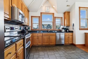 A kitchen with wooden cabinets, a stainless steel range, and a dishwasher. - Ocean Paradise -- Spacious 7BR Oceanfront with Pool, Hot Tub and More! (Corolla)