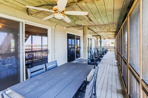 Un espace extérieur abrité, aménagé avec des tables et des chaises, doté d’un ventilateur de plafond et offrant une vue sur la plage.