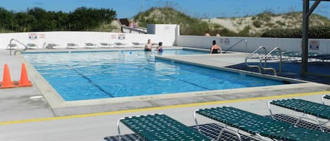 Piscina con varias pistas de natación, sillas de descanso y una zona cubierta.