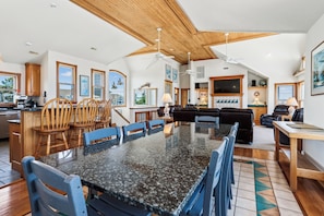 A spacious kitchen with a large island, wooden chairs, and a dining table. - Ocean Paradise -- Spacious 7BR Oceanfront with Pool, Hot Tub and More! (Corolla)