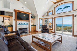 A spacious living room with a fireplace, leather sofa, and a large television.