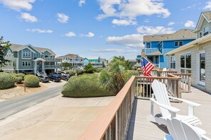 Una zona residenziale sulla costa, con case, un pontile di legno con sedie e bandiere americane.