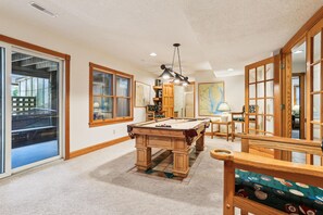 Une pièce spacieuse avec une table de billard, des meubles en bois et de grandes fenêtres.