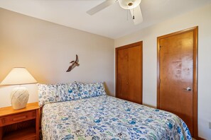 Un dormitorio con una cama, una mesita de noche, una lámpara y dos puertas de madera.