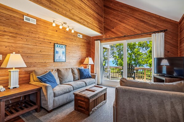 A cozy living room with a wooden ceiling, a sofa, a coffee table, and a television.