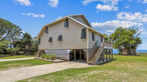 A two-story house with a covered porch and a staircase leading to a deck. - Emerald Duck -- Awesome Sunset and Water Views Soundfront Duplex (Duck)