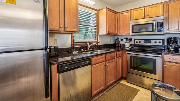 A kitchen with wooden cabinets, stainless steel appliances, a microwave, and a dishwasher. - Emerald Duck -- Awesome Sunset and Water Views Soundfront Duplex (Duck)