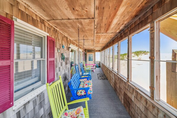 A covered outdoor seating area with wooden walls and large windows.