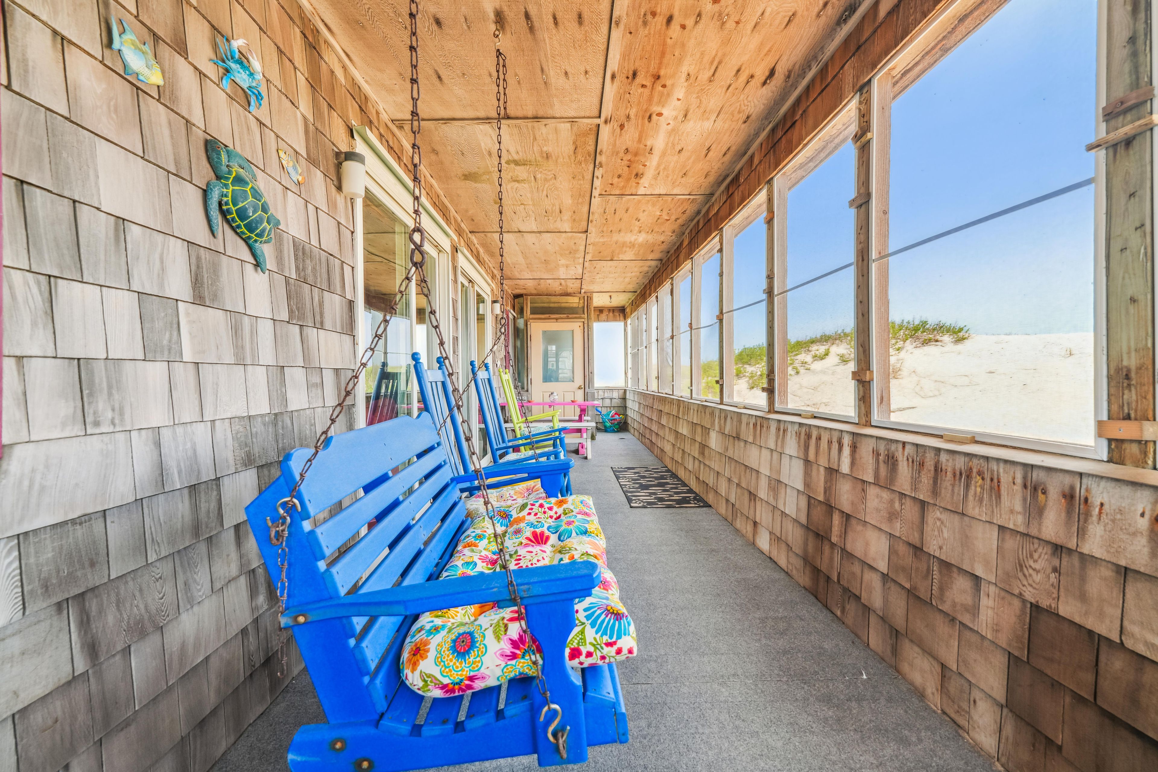 A covered walkway with wooden walls, benches, and a view of the beach.