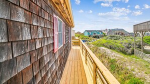 A wooden deck with a view of beach houses and vegetation.