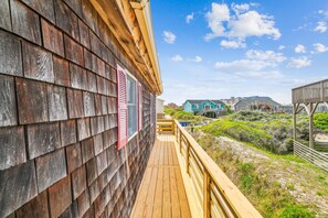 Una terraza de madera con vistas a casas de playa y vegetación.
