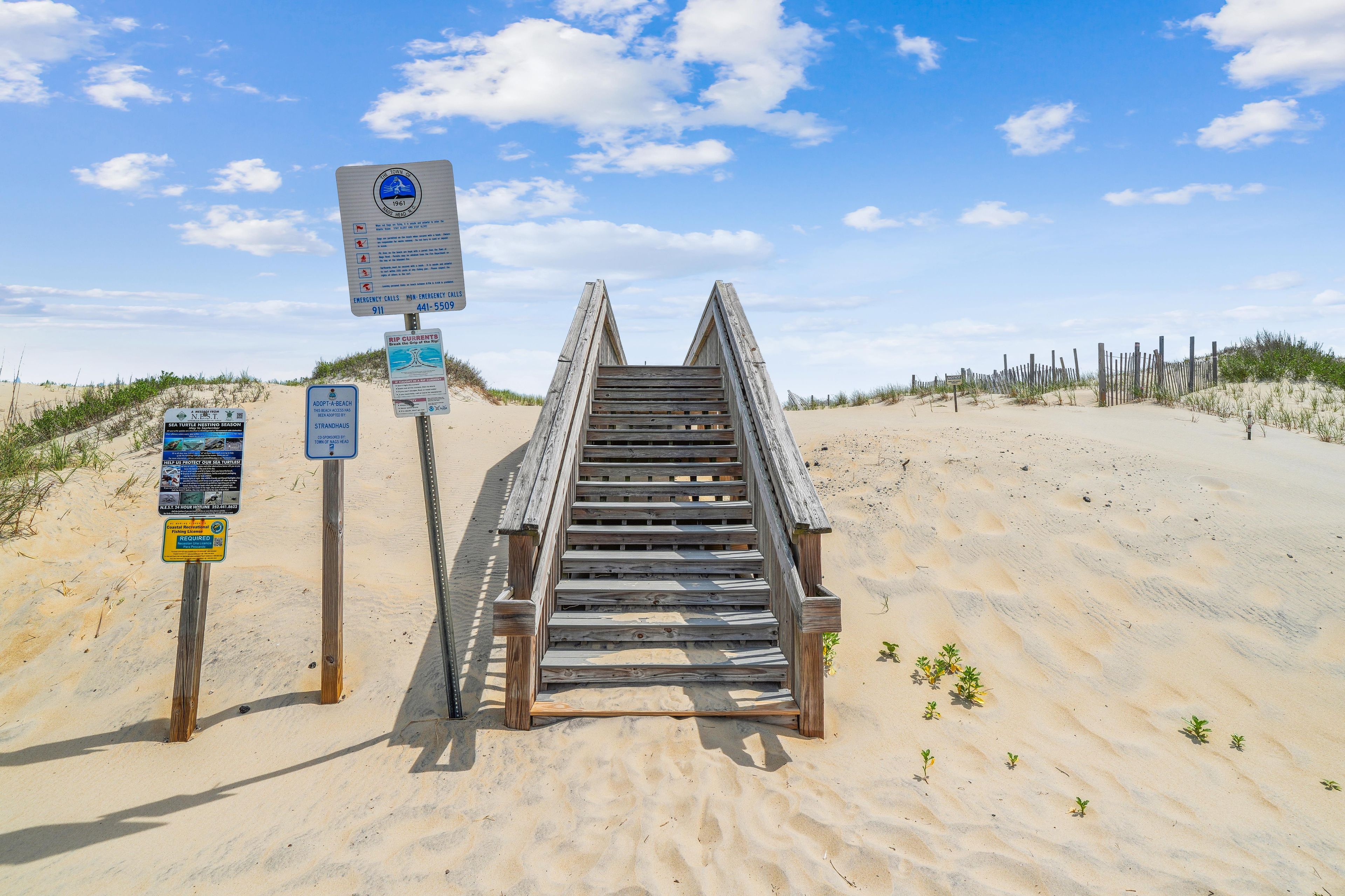 Un escalier en bois menant à une plage, agrémenté de panneaux d ’information.