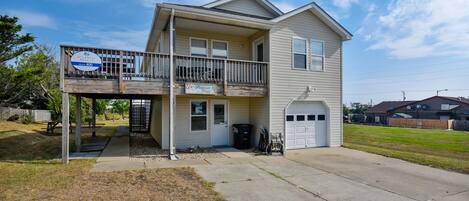 A two-story residential building with a balcony, a garage, and a front yard.