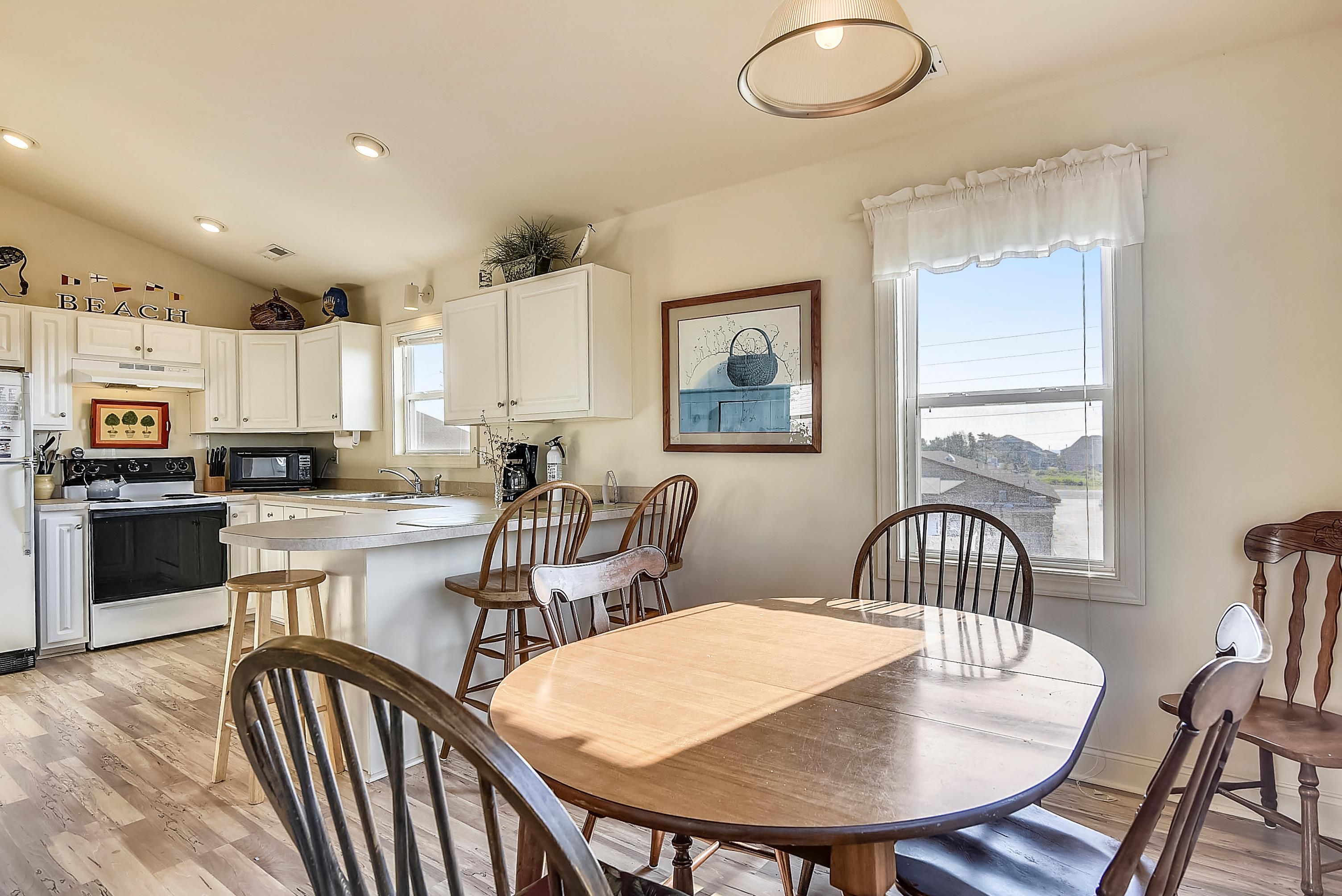 A kitchen with white cabinets, a dining table with chairs, and a window with a view.