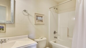A bathroom with a sink, toilet, bathtub, and a shower curtain. - Premium Tripp -- Close to Shopping, Restaurants and Activities (Kill Devil Hills)