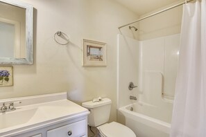 Une salle de bain équipée d’un lavabo, de toilettes, d’une baignoire et d’un rideau de douche.