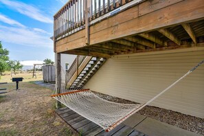 A wooden deck with a hammock, a staircase, and a garage door. - Premium Tripp -- Close to Shopping, Restaurants and Activities (Kill Devil Hills)