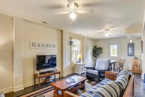 A living room with a television, a sofa, a coffee table, and a ceiling fan. - Premium Tripp -- Close to Shopping, Restaurants and Activities (Kill Devil Hills)
