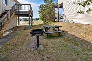 Un jardin avec un barbecue, une table de pique-nique et une terrasse en bois.