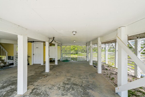 A covered outdoor area with a concrete floor, white structural columns, and a yellow wall.