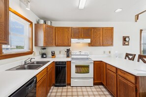 A kitchen with wooden cabinets, a dishwasher, a stove, and a sink.