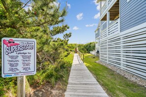 A wooden boardwalk leading to a beach area with a sign pledging to maintain cleanliness and safety.