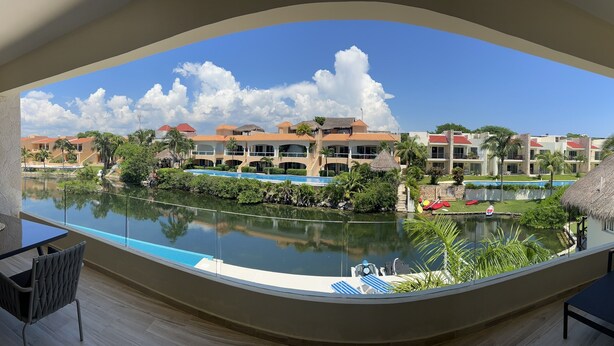 Vista de um resort com piscina, espreguiçadeiras e uma construção de telhado de palha.