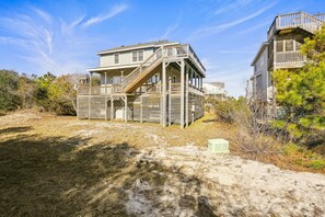 A two-story wooden house with a balcony and a staircase leading to the upper level.