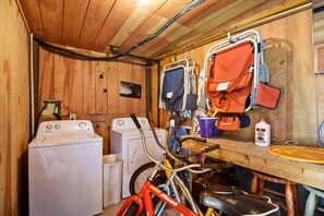 Un espace dédié à la lessive, comprenant un lave-linge, un vélo et divers produits de nettoyage.