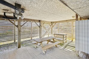 A covered outdoor area with a picnic table and benches, wooden beams, and a metal pipe structure.
