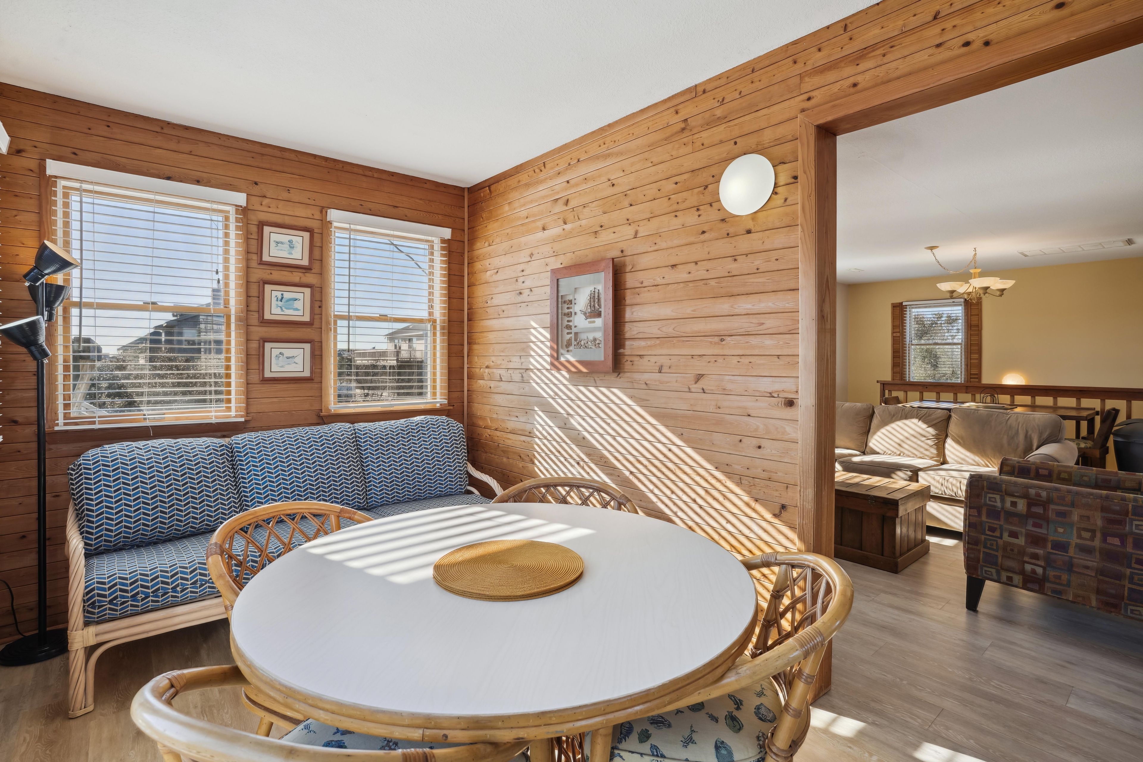 A cozy room with a round table, wicker furniture, and framed pictures on the wall.