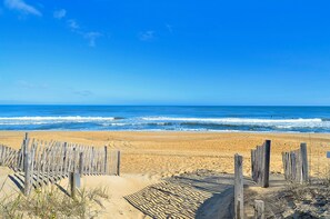 A beach with a wooden fence and the ocean in the background.