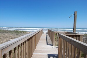 A wooden boardwalk leading to the beach with a clear view of the ocean.