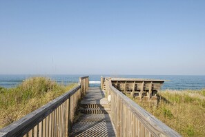 Una pasarela de madera que conduce a una playa con vista despejada al océano.