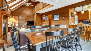 A wooden interior with a dining area, kitchen, and a staircase.