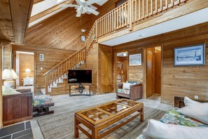 A spacious wooden interior with a staircase, a television, and a sofa. - Timberland -- 4 BR Oceanside home in Southern Duck (Duck)